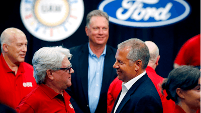 In this Monday, July 15, 2019, file photo, United Auto Workers Local 600 President Bernie Ricke, left, talks with Ford Motor Co., President Automotive Joseph R. Hinrichs after opening contract talks in Dearborn, Mich. The United Auto Workers union said late Wednesday, Oct. 30 that it has reached a tentative contract agreement with Ford after three days of intense bargaining.