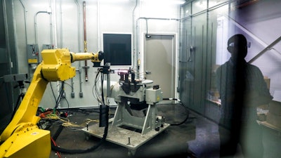 In this May 18, 2017, file photo, a robotic arm with a high-intensity blowtorch is remotely operated to test ceramic matrix composites, which make engines more durable, heat-resistant and efficient, at the General Electric Aviation plant in Evendale, Ohio. General Electric Co. said Monday, Oct. 7, 2019, that it will freeze its pension plan for about 20,700 salaried workers as part of its debt-cutting plan.