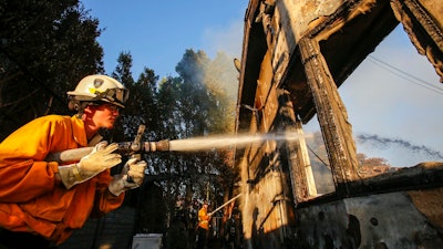 Firefighters work on a house destroyed by a wildfire called the Getty Fire in Los Angeles, Monday, Oct. 28, 2019.