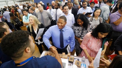 In this Sept. 17, 2019, file photo job seeker Cedric Edwards, center, shakes hands with recruiter Allen Lewis, left, during an Amazon job fair in Dallas. On Wednesday, Oct. 2, payroll processor ADP reports how many jobs private employers added in September.