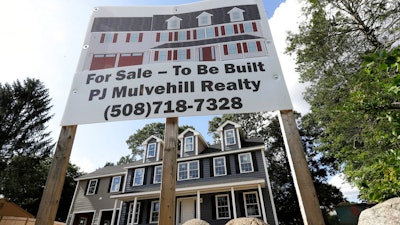 In this Sept. 3, 2019 photo a for sale sign, top, rests in front of a newly constructed home, in Norwood, Mass. On Thursday, Oct. 17, the Commerce Department reports on U.S. home construction in September.