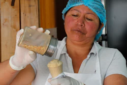 In this Sept. 28, 2019 photo, Maria del Carmen Pilapana tops a scoop of a guinea pig flavored ice cream with peanuts, at her stall on the outskirts of Quito, Ecuador.