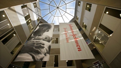 In this July 30, 2013, file photo, large banners hang in an atrium at the headquarters of Johnson & Johnson in New Brunswick, N.J. Johnson & Johnson has become the latest company to settle a lawsuit to get out of the first federal trial over the nation's opioids crisis, reaching a deal worth more than $20 million with two Ohio counties, the company announced Tuesday, Oct. 1, 2019.