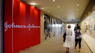 In this July 30, 2013, file photo, people walk along a corridor at the headquarters of Johnson & Johnson in New Brunswick, N.J. A Philadelphia jury has ruled that Johnson & Johnson and Janssen Pharmaceuticals must pay $8 billion in punitive damages over an antipsychotic drug linked to the abnormal growth of female breast tissue in boys. A law firm for the plaintiff released a statement Tuesday, Oct. 8, 2019, saying the companies used an organized scheme to make billions of dollars while illegally marketing and promoting the drug called Risperdal.