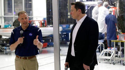NASA Administrator Jim Bridenstine, left, talks with SpaceX chief engineer Elon Musk, right, in front of the Crew Dragon spacecraft, about the progress to fly astronauts to and from the International Space Station, from American soil, as part of the agency's commercial crew program at SpaceX headquarters, in Hawthorne, Calif., Thursday, Oct. 10, 2019.