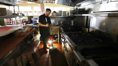 In this Oct. 10, 2019, file photo, Salvador Espinosa sweeps in the kitchen of a Mary's Pizza Shack restaurant during a Pacific Gas and Electric Co. power shutdown in Santa Rosa, Calif. The California Senate will investigate a California utility's process for cutting off power to more than 2 million people to prevent wildfires. In a memo to the Senate Democratic Caucus on Thursday, Oct. 17, 2019, Senate President Pro Tempore Toni Atkins asked the Senate Energy, Utilities, and Communications Committee to 'begin investigating and reviewing options to address the serious deficiencies' with PG&E's current process of shutting off power to prevent wildfires.