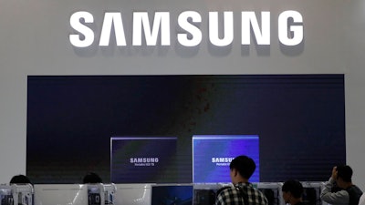 Visitors tour near the logo of Samsung Electronics at semiconductor exhibition in Seoul, South Korea, Tuesday, Oct. 8, 2019. Samsung Electronics has predicted its operating profit for the last quarter will fall by more than 56% from a year earlier amid sluggish global demand for computer chips.