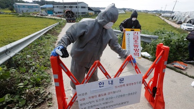 Quarantine officials wearing protective gears place barricades as a precaution against African swine fever at a pig farm in Paju, South Korea.