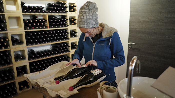 In this photo taken on Wednesday, Nov. 13, winemaker Claire Chasselay lays the labels on bottles of wine in her cellar in Chatillon d'Azergues, in the Beaujolais region, eastern France.