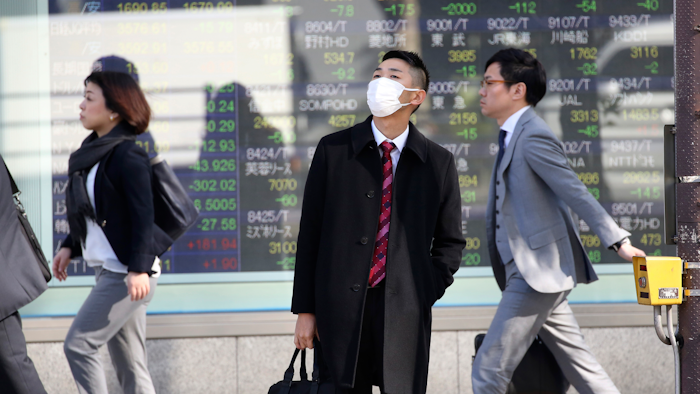 In this Nov. 21 photo, people walk in front of an electronic stock board of a securities firm in Tokyo.