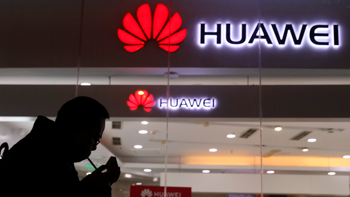 In this Dec. 6, 2018 file photo, a man lights a cigarette outside a Huawei retail shop in Beijing.