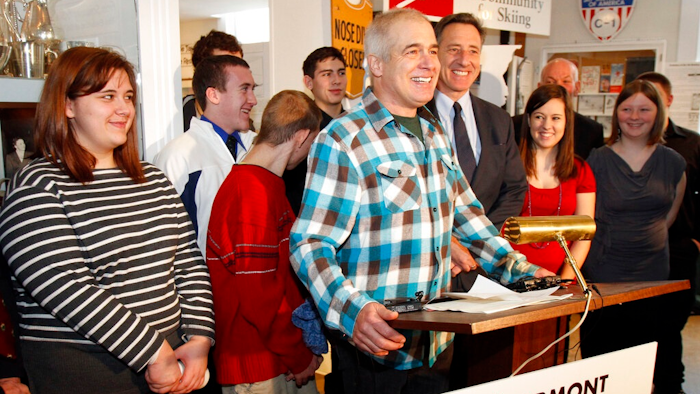In this March 8, 2012, file photo, Jake Burton Carpenter, the creator of Burton Snowboards, center, speaks during a bill signing with Gov. Peter Shumlin, to the right of Burton, in Stowe, Vt. Shumlin signed a bill making skiing and snowboarding the official state sports of Vermont. Carpenter, the innovator who brought the snowboard to the masses and helped turn the sport into a billion-dollar business, has died after a recurring bout with cancer. He was 65. Officials from the company he founded, Burton Snowboards, told The Associated Press of his death Thursday, Nov. 21, 2019.