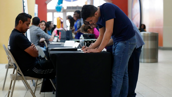 In this Oct. 1, 2019, file photo Billy Ramos, right, fills out a job application with Adidas during a job fair at Dolphin Mall in Miami. On Friday, Nov. 1, the U.S. government issues the October jobs report.