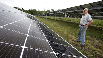 In this Oct. 2 photo, cranberry grower Dick Ward stands near a solar array in a cranberry bog on his farm, in Carver, MA.