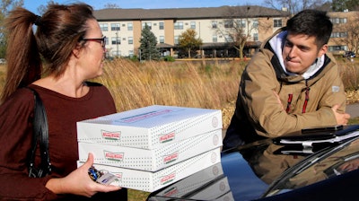 In this Saturday, Oct. 26 photo, Catherine Newton, left, buys three boxes of Krispy Kreme doughnuts from Jayson Gonzalez in Little Canada, MN.