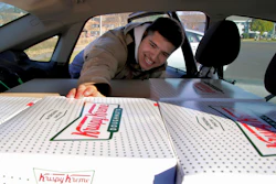In this Oct. 26 photo, Jayson Gonzalez reaches into his car for another box of Krispy Kreme doughnuts for customers in Little Canada, MN, who ordered online.