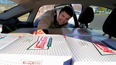In this Oct. 26 photo, Jayson Gonzalez reaches into his car for another box of Krispy Kreme doughnuts for customers in Little Canada, MN, who ordered online.
