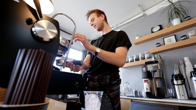 In this Nov. 4 photo, barista Porter Hahn makes an iced coffee drink for a customer in a coffee shop in Seattle.