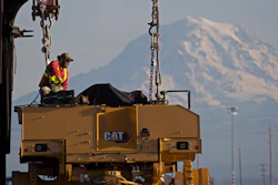 In this Nov. 4, 2019 photo, a worker prepares a piece of Cat construction equipment made by Caterpillar to be lifted off a trailer at the Port of Tacoma in Tacoma, WA.