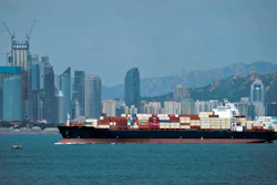 In this Sept. 13, 2018 file photo, a container ship sails by the business district in Qingdao in east China's Shandong province.