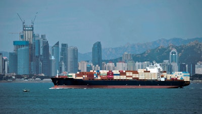 In this Sept. 13, 2018 file photo, a container ship sails by the business district in Qingdao in east China's Shandong province.