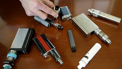 In this April 10, 2018 file photo, a high school principal displays vaping devices that were confiscated from students in such places as restrooms or hallways at the school in Massachusetts.