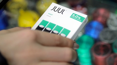 In this Dec. 20, 2018, file photo a woman buys refills for her Juul at a smoke shop in New York.