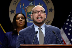 East Hampton High School Principal Adam Fine speaks as New York State Attorney General Letitia James, rear left, listens during a news conference at her office in New York on Tuesday, Nov. 19.