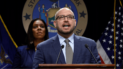 East Hampton High School Principal Adam Fine speaks as New York State Attorney General Letitia James, rear left, listens during a news conference at her office in New York on Tuesday, Nov. 19.