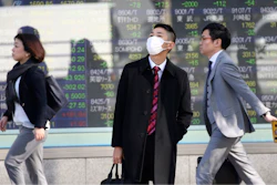 In this Nov. 21 photo, people walk in front of an electronic stock board of a securities firm in Tokyo.