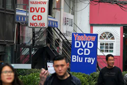 In this April 27, 2016 file photo, people walk past a shop selling pirated movie DVDs and music CDs in Beijing.