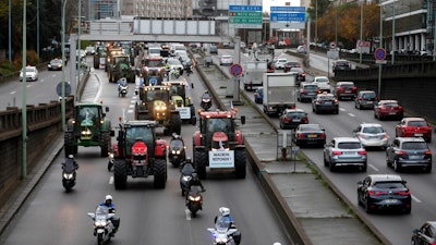 Farmer drive their tractors on the Paris ring road in Paris on Wednesday, Nov. 27. French farmers are driving tractors into Paris and Lyon to protest stagnant revenues and unfair competition. The placard reads « Save your farmer ».