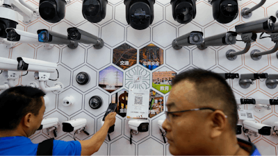 In this Oct. 29, 2019 photo, visitors look at the surveillance cameras and services provided by China's telecoms equipment giant Huawei on display at the China Public Security Expo in Shenzhen, China's Guangdong province.