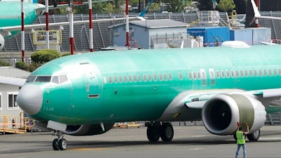 In this May 8, 2019, file photo workers stand near a Boeing 737 MAX 8 jetliner being built for American Airlines prior to a test flight in Renton, Wash. American Airlines CEO Doug Parker says his airline is feeling more confident that its grounded Boeing 737 Max jets will soon be approved to fly again.