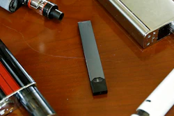 This Tuesday, April 10, 2018 file photo shows vaping devices, including a Juul, center, that were confiscated from students at a high school in Marshfield, MA.