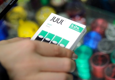 In this Dec. 20, 2018, file photo a woman buys refills for her Juul at a smoke shop in New York. The e-cigarette maker Juul Labs said Thursday, Nov. 7, 2019, that it will halt sales of its best-selling mint-flavored vaping pods.