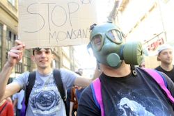 Protesters hold signs critical of agro-giant Monsanto.