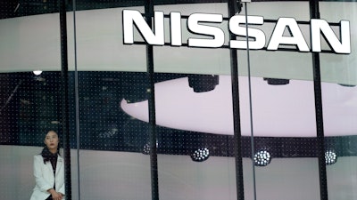 In this photo, a staff member stands by a window of a Nissan car gallery in Tokyo. Japanese automaker Nissan has seen July-September profit tumble to half of what it earned the previous year as sales and brand power crumbled since the arrest of former Chairman Carlos Ghosn a year ago.