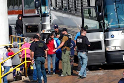 In this Wednesday, Aug. 7, 2019, file photo, handcuffed workers are escorted into a bus for transportation to a processing center following a raid by U.S. immigration officials at a Koch Foods Inc., plant in Morton, Miss. Three months after immigration agents arrested 680 Latino workers in a massive workplace sting at seven Mississippi chicken processing plants, a congressional committee plans a hearing into the raids and their effects, Thursday, Nov. 7, in Jackson, Miss.
