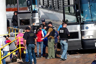 In this Wednesday, Aug. 7, 2019, file photo, handcuffed workers are escorted into a bus for transportation to a processing center following a raid by U.S. immigration officials at a Koch Foods Inc., plant in Morton, Miss. Three months after immigration agents arrested 680 Latino workers in a massive workplace sting at seven Mississippi chicken processing plants, a congressional committee plans a hearing into the raids and their effects, Thursday, Nov. 7, in Jackson, Miss.