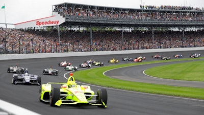 In this May 26, 2019, file photo, Simon Pagenaud, of France, leads the field through the first turn on the start of the Indianapolis 500 IndyCar auto race at Indianapolis Motor Speedway, in Indianapolis. Indianapolis Motor Speedway and the IndyCar Series have been sold to Penske Entertainment Corp. in a stunning announcement that relinquishes control of the iconic speedway from the Hulman family after 74 years.