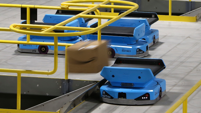 In this Dec. 17 photo, an Amazon robot sends a package down a chute, transporting packages from workers to chutes that are organized by zip code, at an Amazon warehouse facility in Goodyear, AZ. The tech giant is still rolling out new models descended from the Kiva line, including the Pegasus, a squarish vehicle with a conveyor belt on top that can be found working the early-morning shift at a warehouse in the Phoenix suburb of Goodyear.