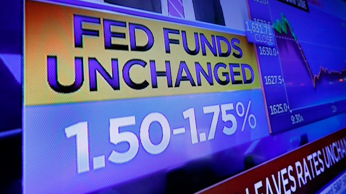 A television screen on the floor of the New York Stock Exchange shows the rate decision of the Federal Reserve, Wednesday, Dec. 11, 2019. The Federal Reserve is leaving its benchmark interest rate alone and signaling that it expects to keep low rates unchanged through next year.