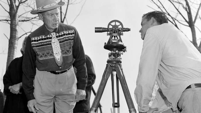 In this April 18, 1958, file photo, Philip N. Brooks, right, a New York State surveyor, takes a look through his transit on the Tuscarora Indian Reservation near Niagara Falls, N.Y., while Tuscarora Chief Elton Black Cloud Greene watches.