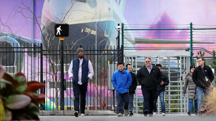 Boeing workers exit the plant in front of a giant mural of a jet on the side of the manufacturing building behind Monday, Dec. 16, 2019, in Renton, Wash. Shares of Boeing fell before the opening bell on a report that the company may cut production of its troubled 737 MAX or even end production all together.
