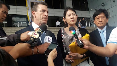 Gerald Margolis, center left, branch manager of Philip Morris in Thailand, talks to reporters at Criminal Court in Bangkok, Thailand on Friday, Nov. 29.