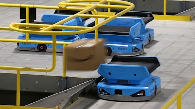 In this Dec. 17 photo, an Amazon robot sends a package down a chute, transporting packages from workers to chutes that are organized by zip code, at an Amazon warehouse facility in Goodyear, AZ. The tech giant is still rolling out new models descended from the Kiva line, including the Pegasus, a squarish vehicle with a conveyor belt on top that can be found working the early-morning shift at a warehouse in the Phoenix suburb of Goodyear.