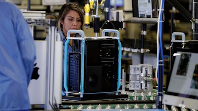 In this Nov. 20, 2019, file photo workers with Apple products being assembled before President Donald Trump tours an Apple manufacturing plant in Austin, Texas. On Monday, Dec. 2, the Institute for Supply Management, an association of purchasing managers, reports on activity by U.S. manufacturers in November.