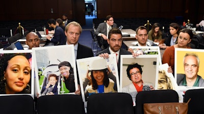In this Oct. 29, 2019, file photo people holding photos of those lost in Ethiopian Airlines Flight 302 and Lion Air Flight 610 wait for the start of a Senate Committee on Commerce, Science, and Transportation hearing on Capitol Hill in Washington.