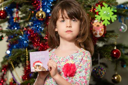 Florence Widdicombe, 6, poses with a Tesco Christmas card from the same pack as a card she found containing a message from a Chinese prisoner, in London, Sunday, Dec. 22, 2019. The U.K.-based grocery chain Tesco has halted production at a factory in China after a British newspaper said it used forced labor to produce charity Christmas cards. Tesco said Sunday it had stopped production and launched an investigation after the Sunday Times newspaper raised questions about the factory's labor practices.